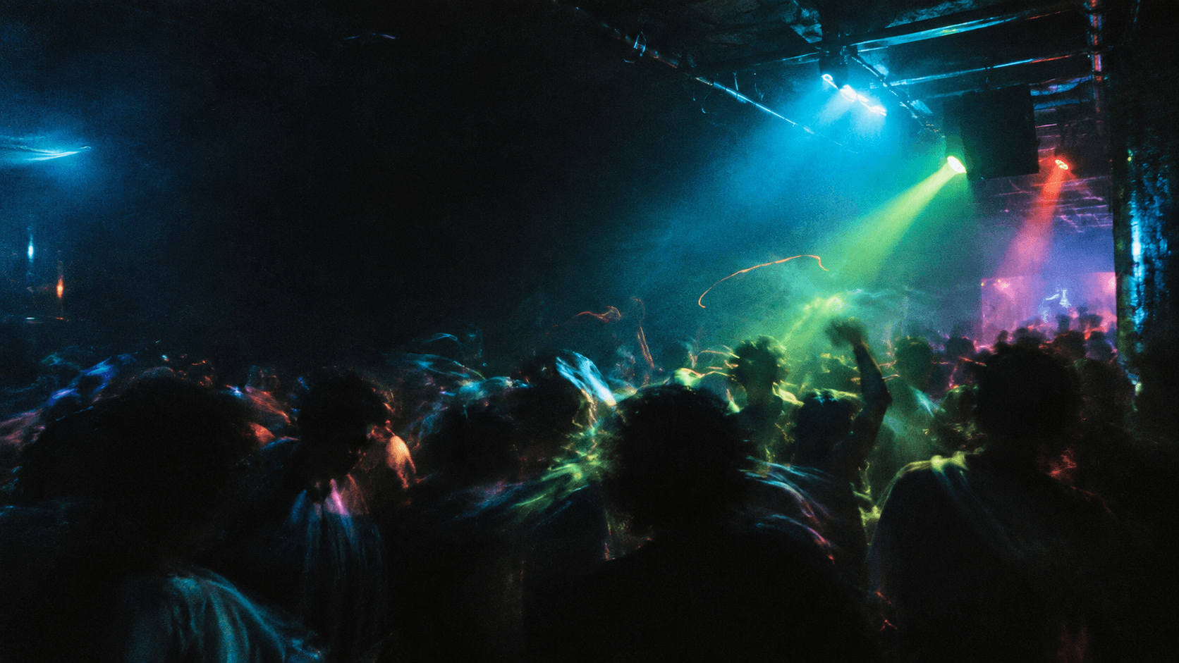 Crowd moving through cyan, red and green light